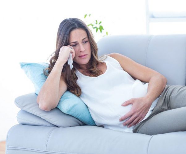 Беременная женщина лежит на диване